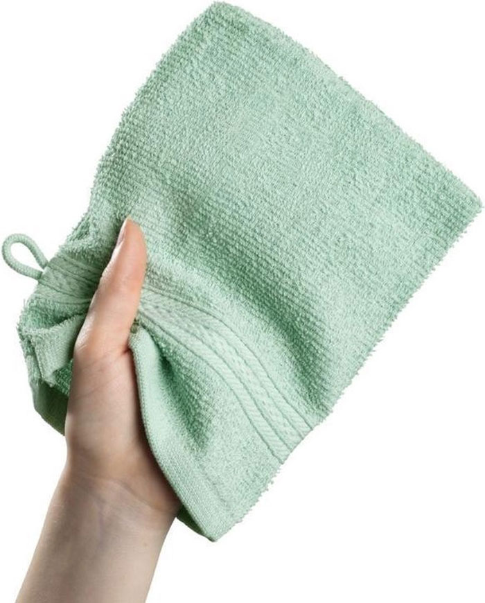 Hand holding a green textured household item cloth unique to certain countries and rarely found elsewhere.