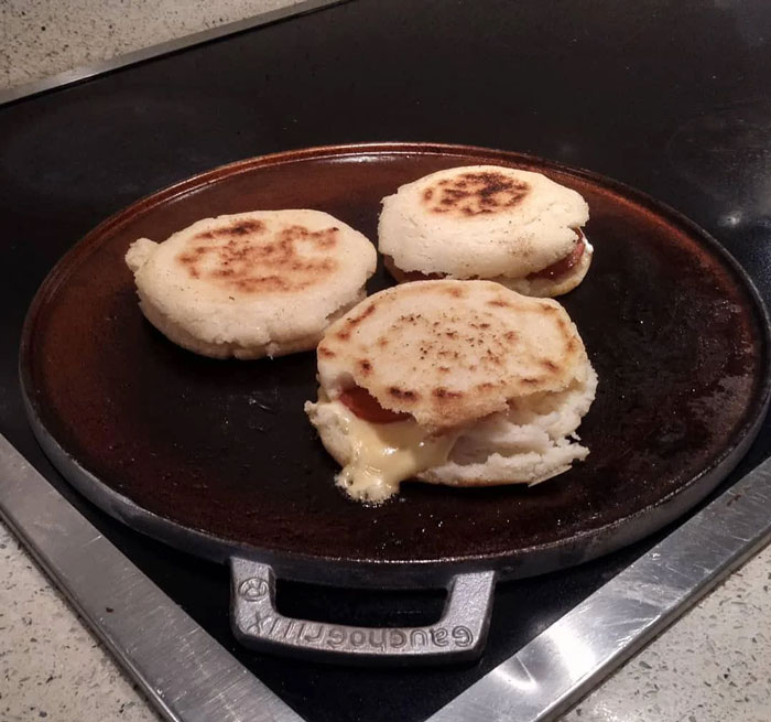 Cast iron griddle with arepas cooking, a unique household item popular in specific countries and rare elsewhere.