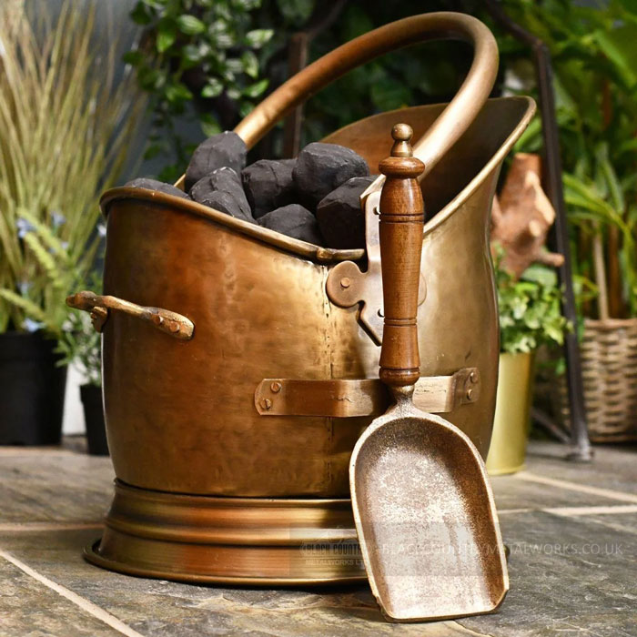Vintage copper coal scuttle with wooden-handled metal scoop, unique household item shared by people from different countries.
