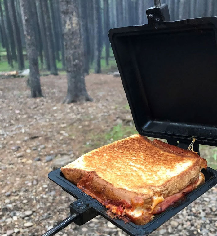 Toasting sandwich in a unique outdoor household item from a country, showcasing rare cooking equipment in natural setting