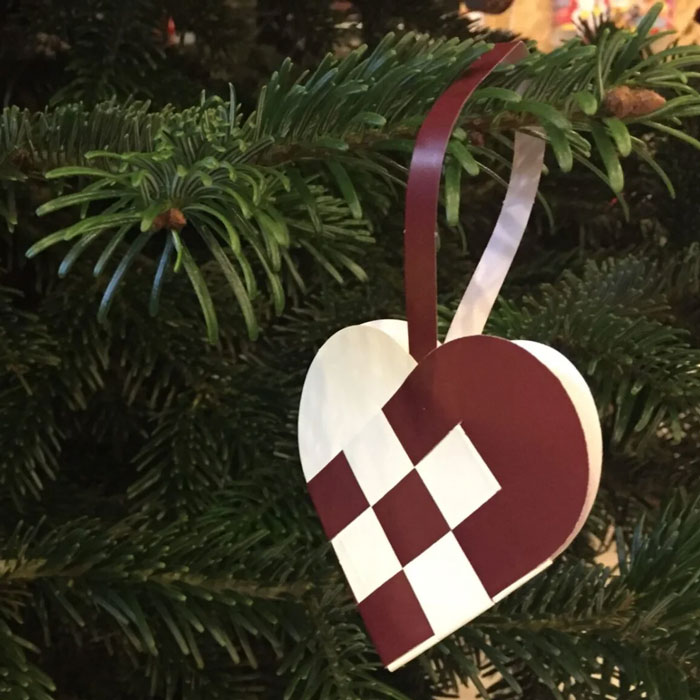 Woven heart-shaped household item hanging on a Christmas tree, unique to certain countries and cultures.