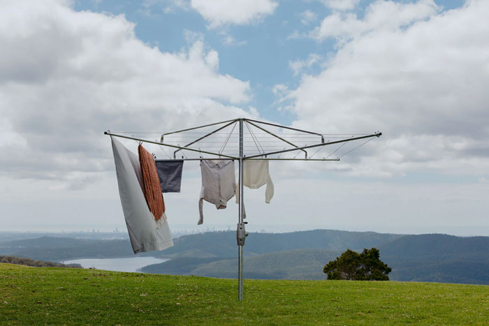 Rotary clothesline for drying laundry outdoors on a grassy hill, a unique household item found in some countries.