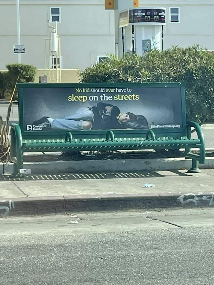 Bus stop bench ad showing a child sleeping on the streets highlighting homelessness in a dystopia reality.