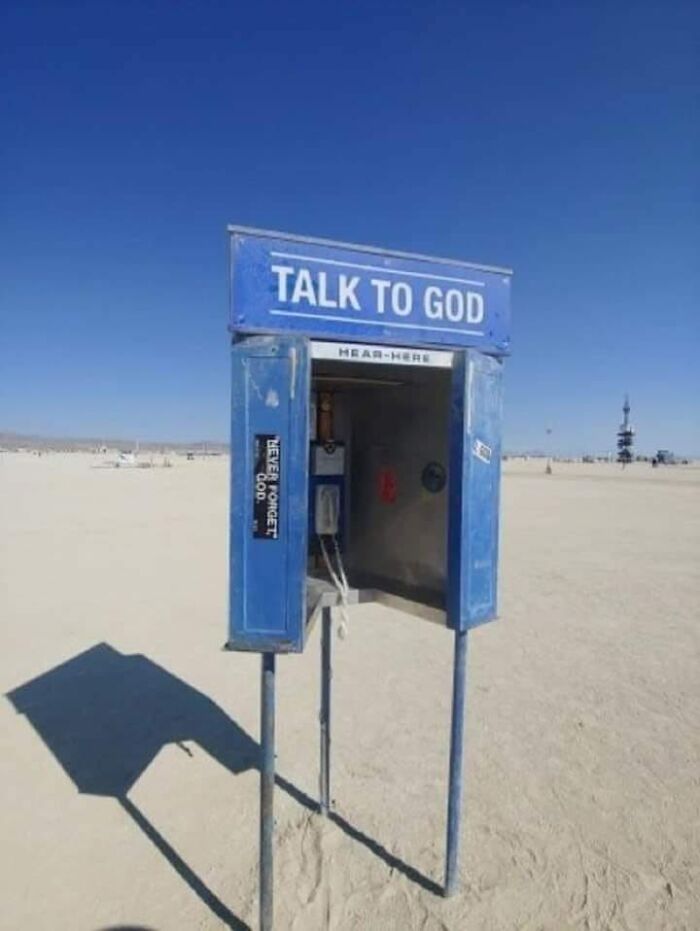 Blue phone booth labeled Talk to God standing alone on a desert plain symbolizing dystopia and surreal normality.