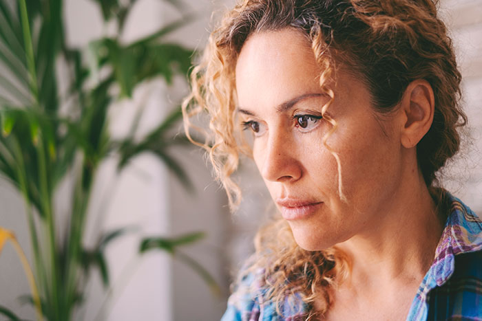 Woman with curly hair looking concerned indoors, reflecting emotional limits after stepdaughters gift and viral conversation.
