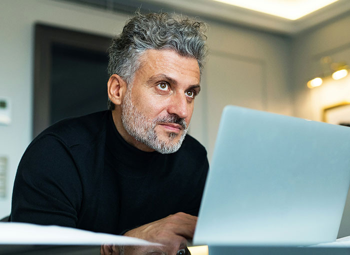 Man with gray hair and beard using a laptop, illustrating a teacher getting schooled by a kid with a fun fact. Man with gray hair and beard using a laptop, illustrating a teacher getting schooled by a kid with a fun fact.