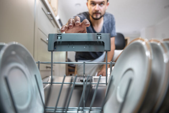 Man loading dishwasher in kitchen, illustrating hygiene anxiety and OCD-like cleaning behavior in family setting. Man loading dishwasher in kitchen, illustrating hygiene anxiety and OCD-like cleaning behavior in family setting.