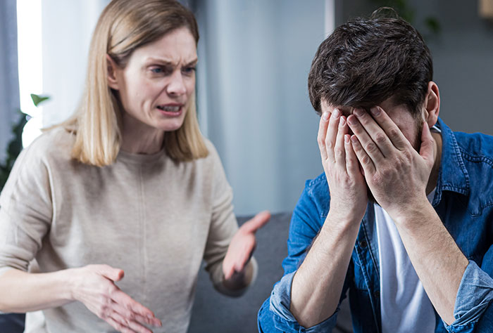 Man feeling torn between his husband and mother-in-law during a tense argument in a home setting.