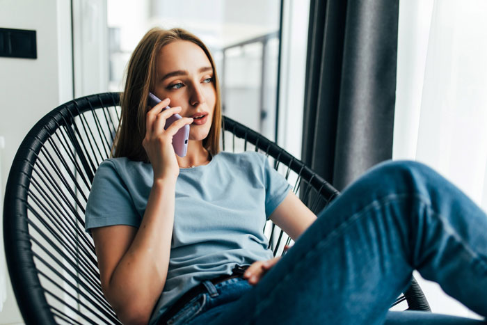 Young woman in casual clothes sitting in chair, making a phone call while using Venmo to search fabrications and widow status. Young woman in casual clothes sitting in chair, making a phone call while using Venmo to search fabrications and widow status.