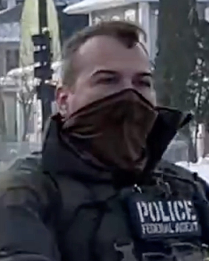 Federal agent wearing a brown face covering and black jacket with police patch in newly released ICE video related to fatal shooting context. Federal agent wearing a brown face covering and black jacket with police patch in newly released ICE video related to fatal shooting context.