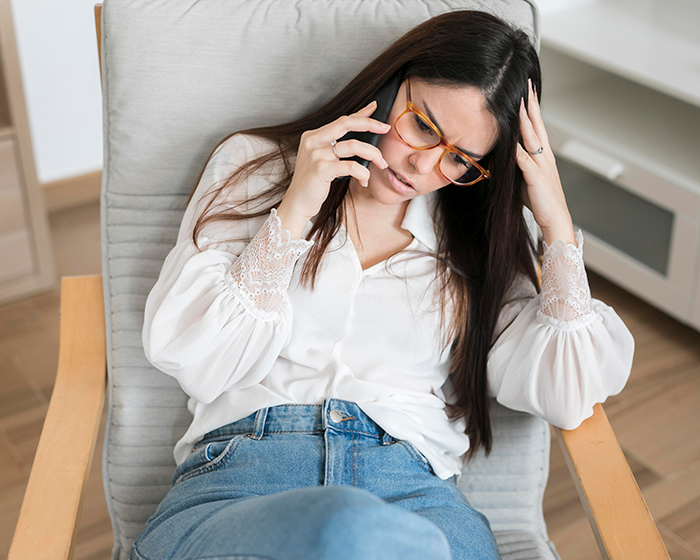 Worried woman wearing glasses sitting and talking on phone, appearing stressed about late BIL Thanksgiving trauma. Worried woman wearing glasses sitting and talking on phone, appearing stressed about late BIL Thanksgiving trauma.