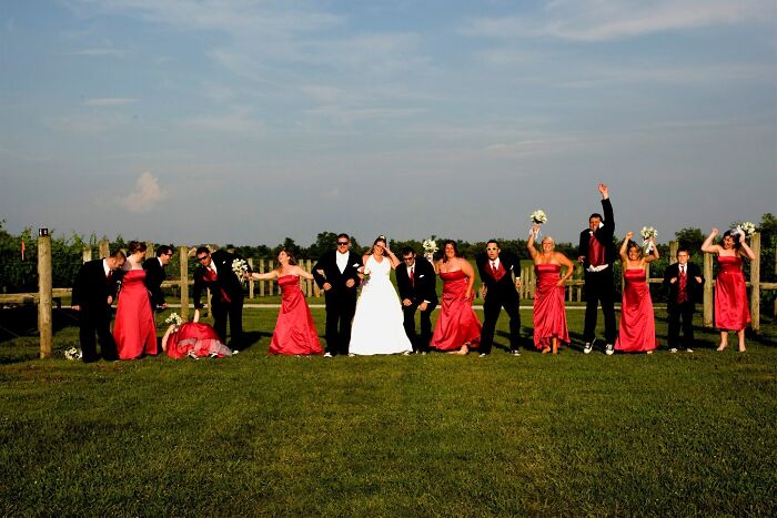 Wedding party in formal attire posing on grass with some awkward and playful moments in awkward wedding photos.