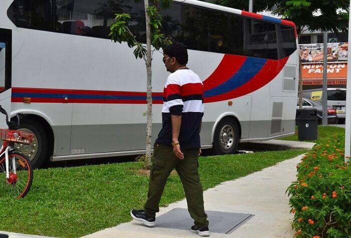 Man walking on sidewalk aligned perfectly with bus colors, demonstrating street photographer's talent for capturing perfect coincidences.