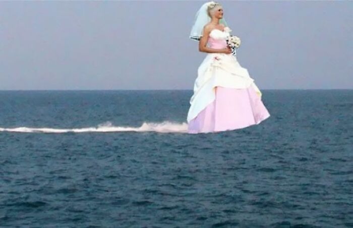Bride in a wedding dress appears to be floating above the ocean in one of the most awkward wedding photos.