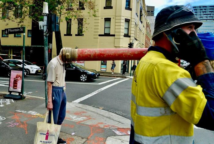 Street photographer capturing perfect coincidences on city streets showing creative moment with construction worker and pedestrian.