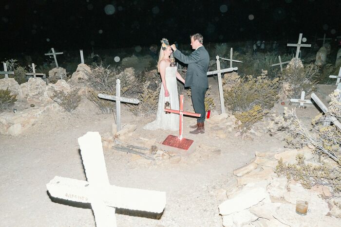 Couple in wedding attire in a graveyard at night, one holding a lantern, street photos capturing life exactly as it happens.