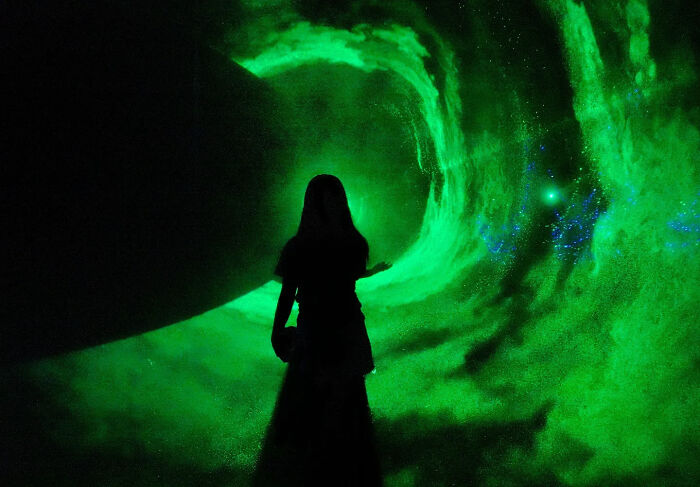 Silhouette of a person standing in front of a swirling green light, showcasing a perfectly timed street shot.