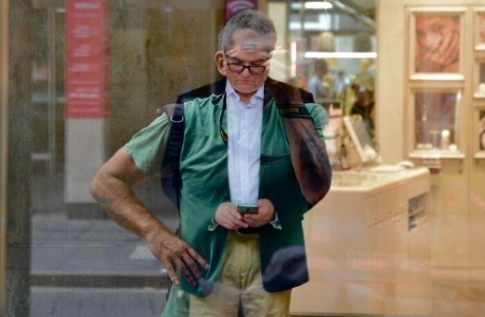 Man reflected in a glass window showing a perfect street photography coincidence captured at just the right moment.