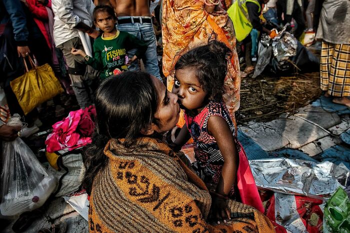 Candid street photo showing tender moment between a mother and child amidst a busy urban crowd capturing humanity and emotion.