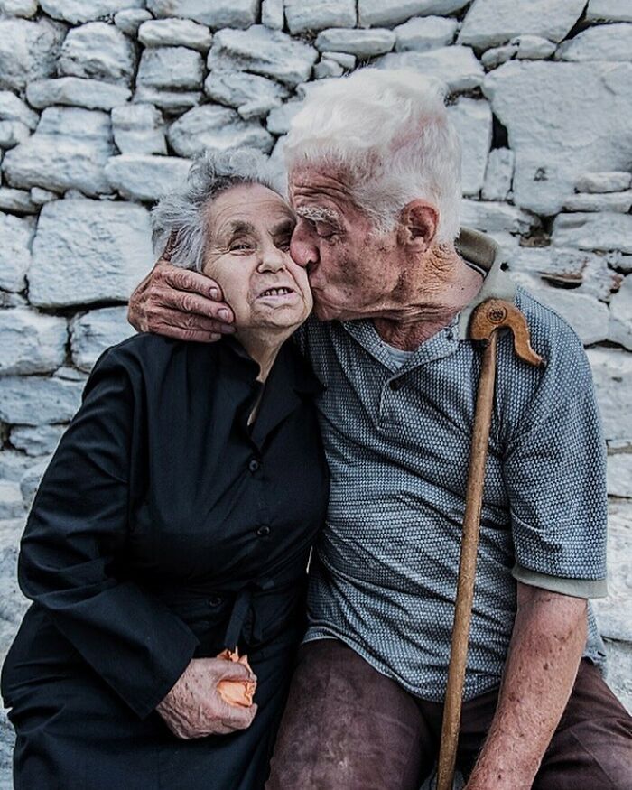 Elderly couple sharing a tender moment, captured in candid street photos showing humanity and affection around the world.