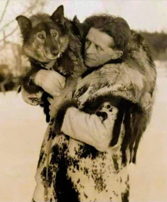 Man in vintage fur coat holding a wolf, capturing a powerful moment in the sad, beautiful history of humanity.