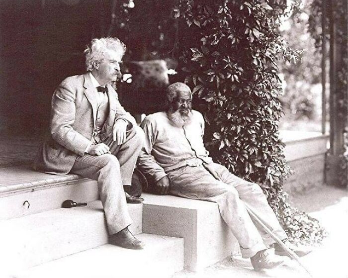 Two men sitting on steps in a historic photograph showing the complex and emotional history of humanity.