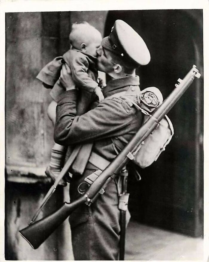 Soldier holding and kissing a baby, a poignant photograph reflecting the sad and beautiful history of humanity.