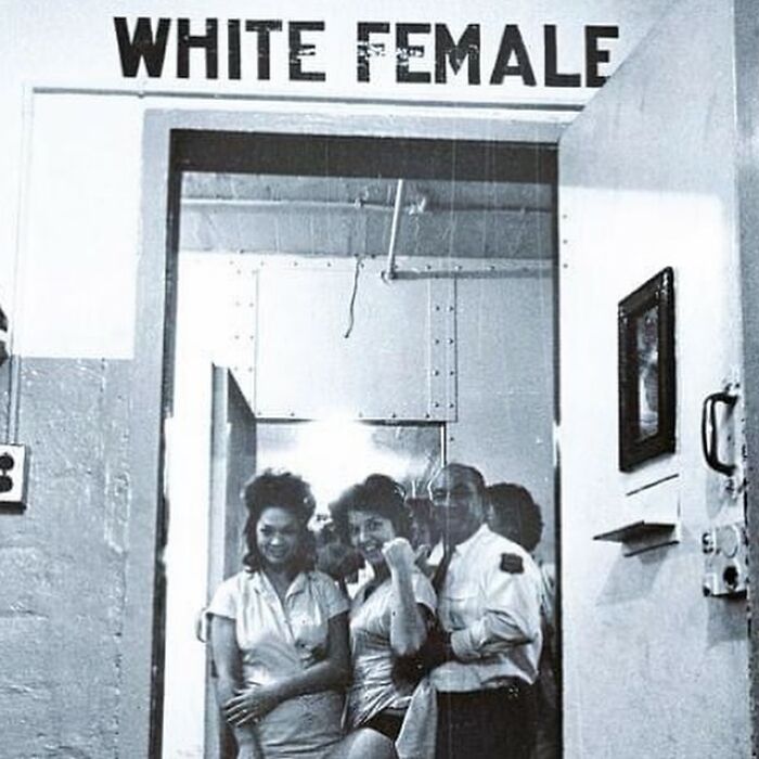 Segregation era photograph showing women waiting under a sign labeled white female, highlighting history of humanity.