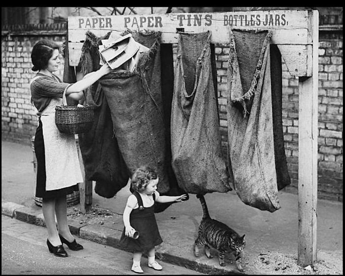 Woman and child sorting recyclable paper and tins into large sacks, showing a glimpse of humanity's historical daily life.