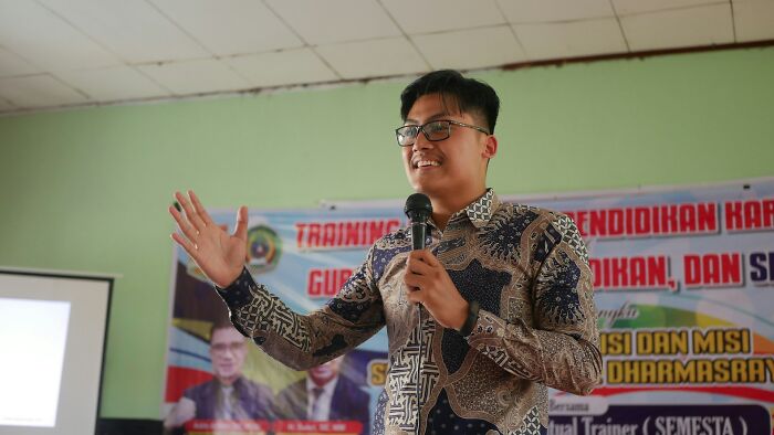 Man holding microphone and speaking in front of a classroom, illustrating weirdest teacher behavior witnessed in class scenarios.