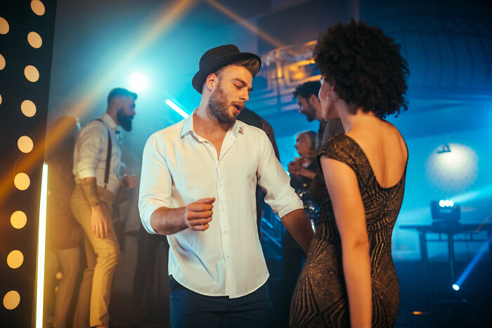 Young people dancing and socializing in a nightclub with vibrant lights showing crazy party stories atmosphere.