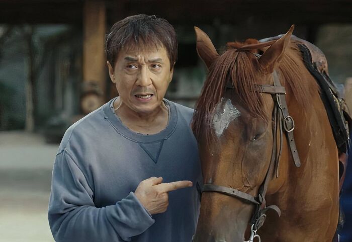 Man in casual clothes pointing at a saddled horse, representing celebs who weren’t nepo babies going from rags to riches.