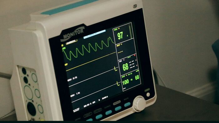 Hospital workers monitor showing patient vitals, heart rate 97, oxygen 100, evoking haunting last words context