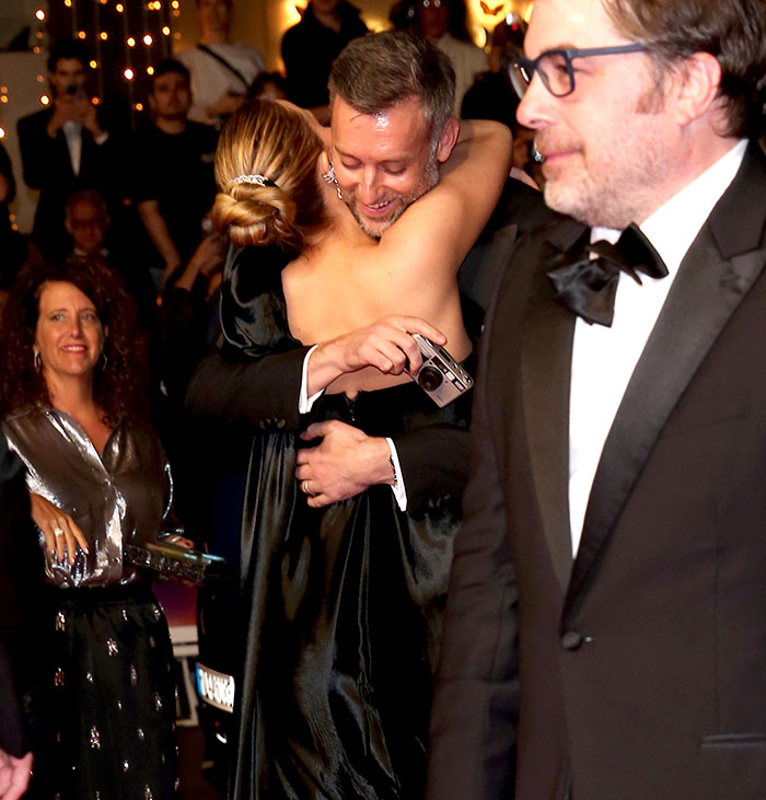 Jennifer Lawrence hugging a man in formal wear at an event, sparking fury after revealing pet rehoming reasons.