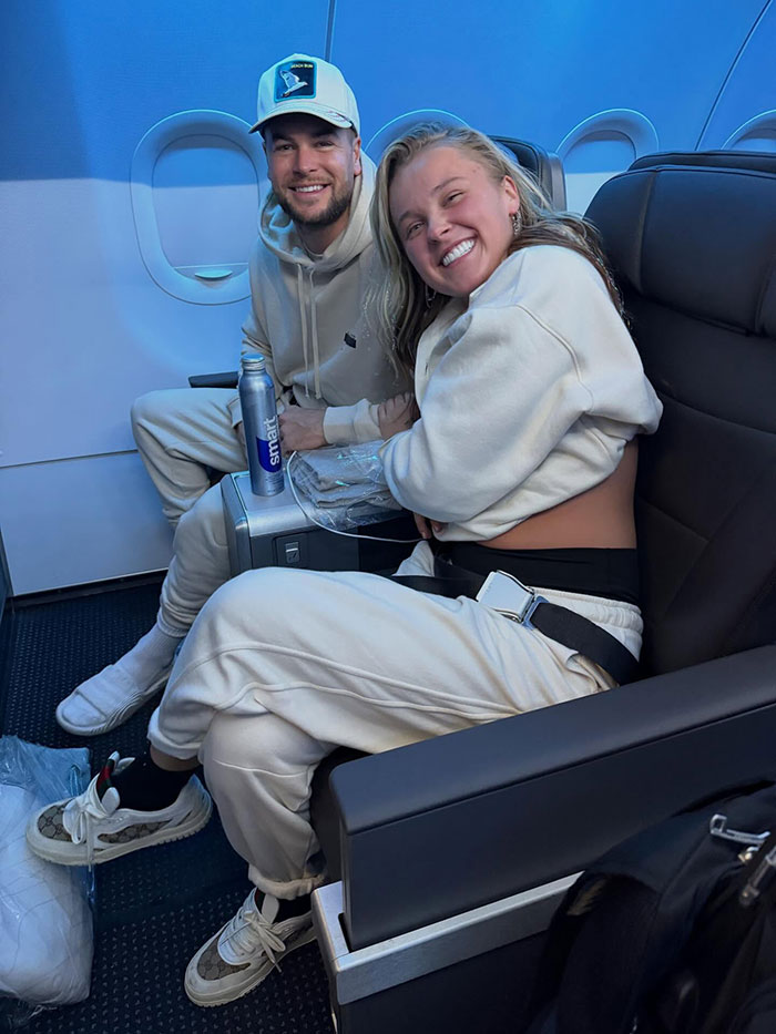 JoJo Siwa smiling and sitting in an airplane seat showcasing her casual style amid massive transformation reactions.