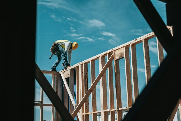 Construction worker wearing safety gear on a wooden frame, showing dramatic behind scenes of people in boring industries.