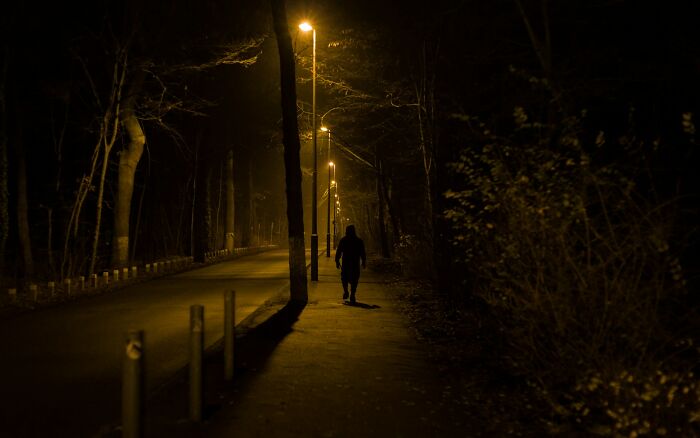 Silhouetted person walking alone on a dimly lit path at night, evoking terrifying real-life moments atmosphere.