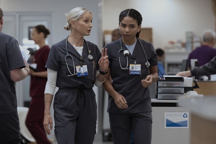 Katherine LaNasa as Nurse Dana in a hospital setting, discussing patient care with a colleague in scrubs.