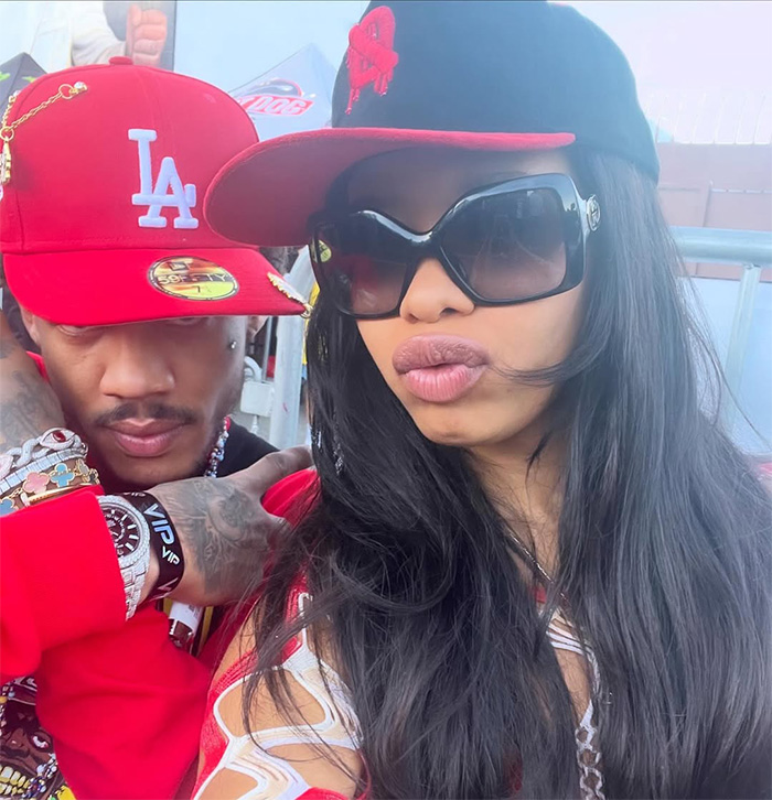 Two adults wearing red and black caps, with one person sporting large black sunglasses in an outdoor setting.