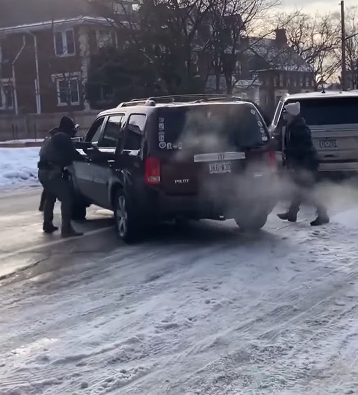 Two individuals in winter clothing near vehicles on a snowy street, relating to Kyle Rittenhouse and ICE slaying news.
