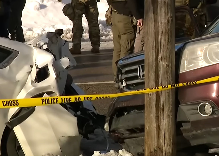 Damaged vehicles behind police tape at an ICE slaying scene in Minneapolis with officers investigating the incident.
