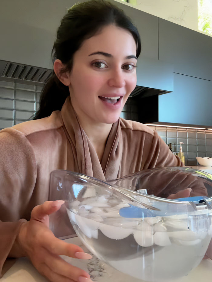 Woman demonstrating Kylie Jenner beauty hack with ice water facial treatment for Botox effects at home.