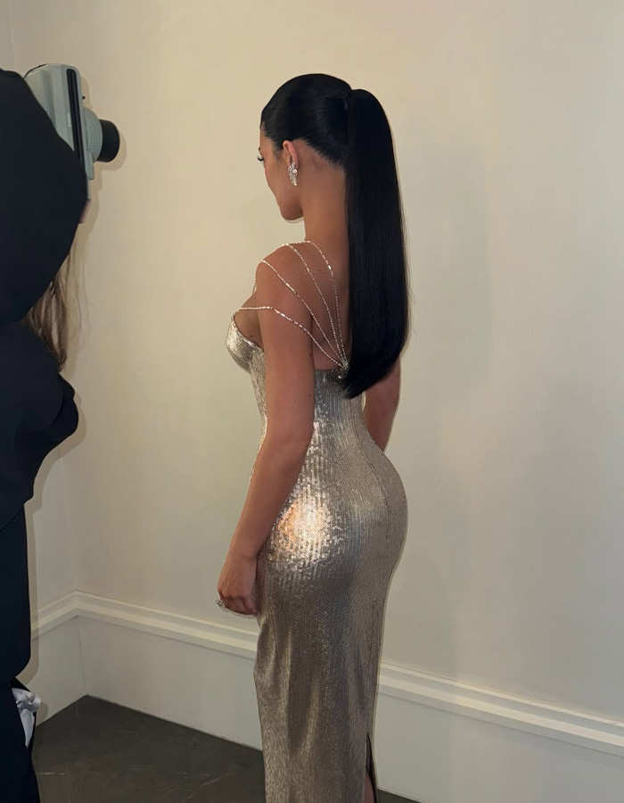 Kylie Jenner in a shimmering gold dress with a sleek ponytail at the Golden Globes sparking debate over her seat photo online.