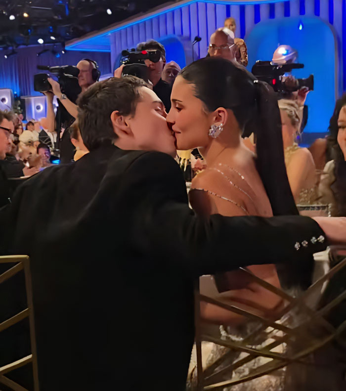 Kylie Jenner at the Golden Globes, showcasing beauty hack reactions amid a glamorous event setting with photographers.