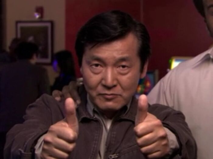 Man giving two thumbs up in a dimly lit room, illustrating a doctor doing something unethical with a patient concept.