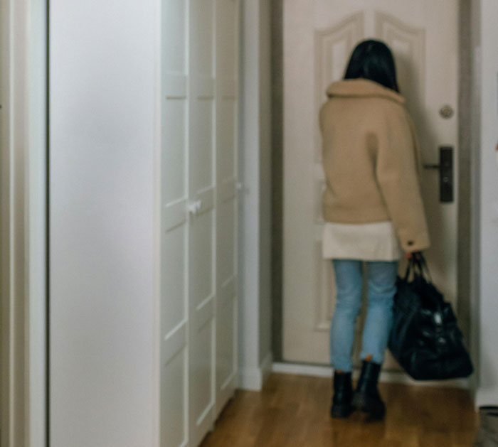 Teen woman standing alone by a closed door, holding a bag, conveying a plan to make him divorce her. Teen woman standing alone by a closed door, holding a bag, conveying a plan to make him divorce her.
