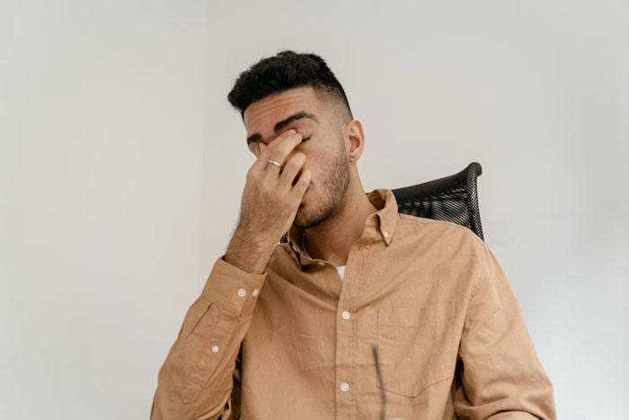 Man sitting in office chair, looking stressed and covering his face, reflecting on dumping girlfriend because she has kids. Man sitting in office chair, looking stressed and covering his face, reflecting on dumping girlfriend because she has kids.