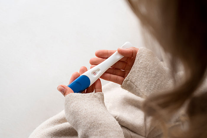 Woman holding a positive pregnancy test, illustrating a man showing his true colors after assuming fiancée is pregnant. Woman holding a positive pregnancy test, illustrating a man showing his true colors after assuming fiancée is pregnant.