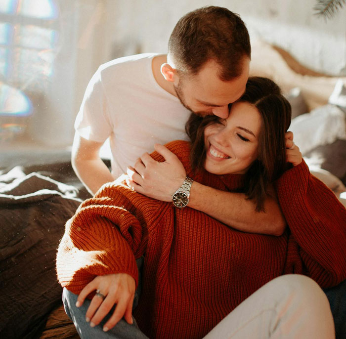 Unemployed woman embraces jobless man warmly indoors, smiling while man kisses her on the head in cozy setting. Unemployed woman embraces jobless man warmly indoors, smiling while man kisses her on the head in cozy setting.