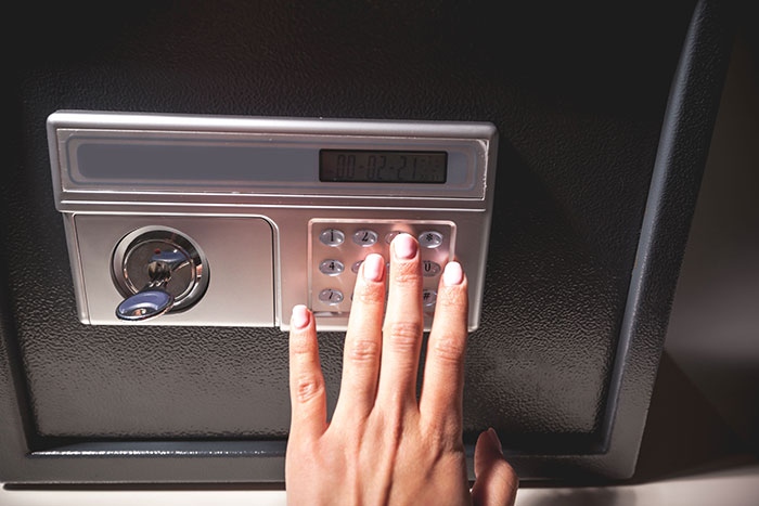 Hand entering code on a safe keypad symbolizing revenge and reckoning in a personal conflict.